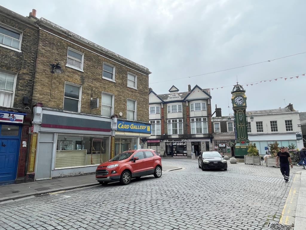 Lot: 14 - FREEHOLD VACANT BUILDING WITH RETAIL PREMISES AND POTENTIAL FOR CONVERSION OF UPPER FLOORS - View towards clock tower showing corner property